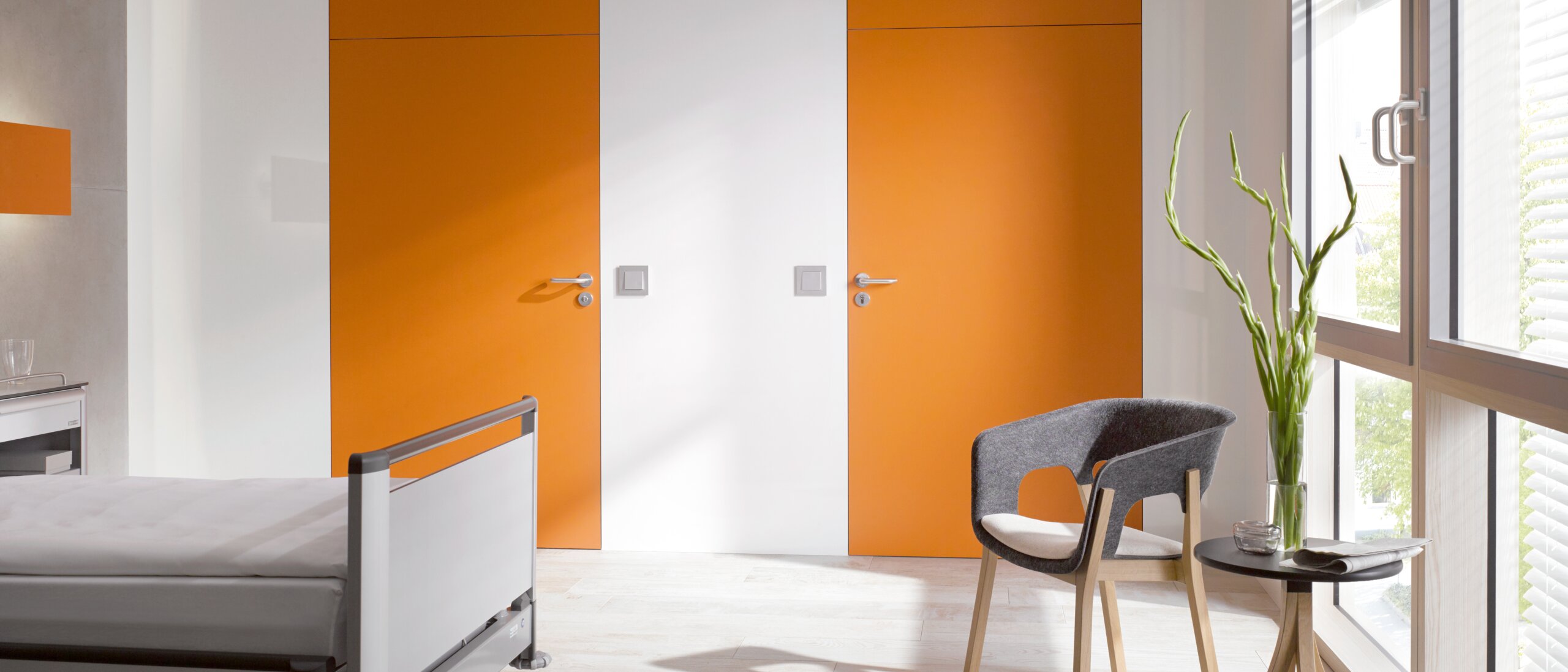 HEWI lever handle 111 White hospital room with two orange doors fitted with a lever handle in the colour grey made of polyamide